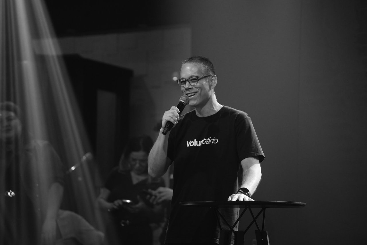 Voluntário apresentando no microfone durante o culto